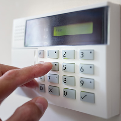 Hand pressing buttons on a modern alarm system keypad.