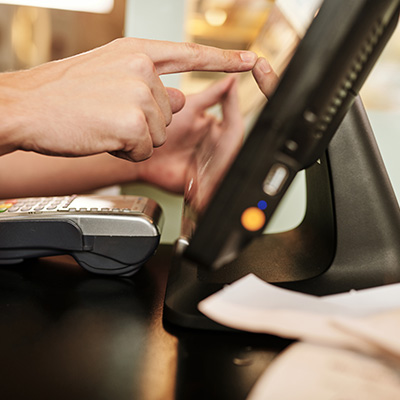 Hand interacting with a touchscreen monitor on a retail stand.
